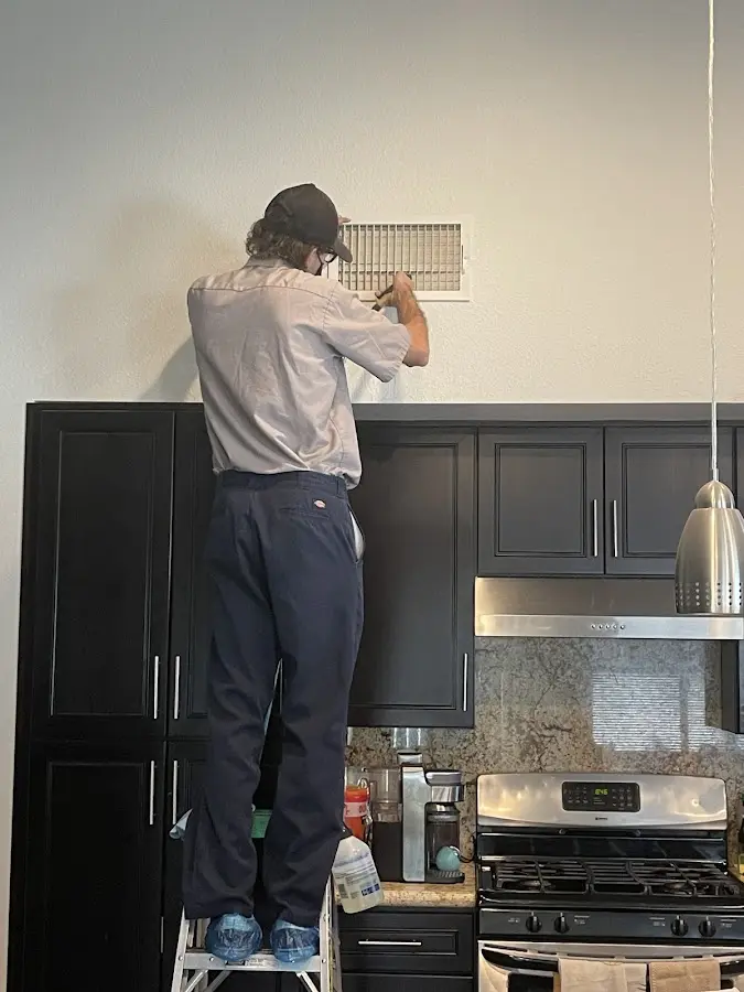 Technician inspecting an air vent during HVAC service in Whitehall